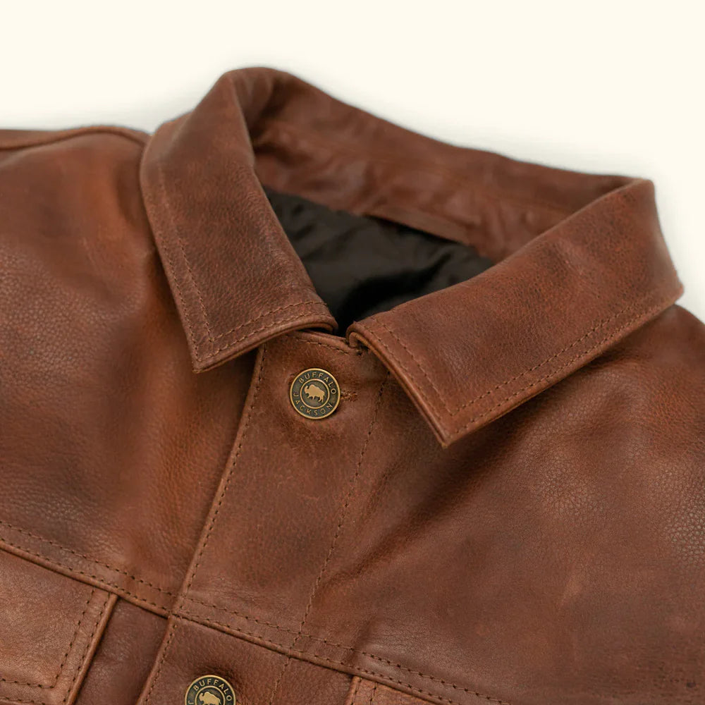 Close-up of antique brass button closures on men's distressed brown leather trucker jacket